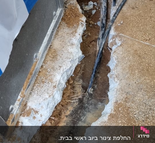 חפירה באדמה עם צינור חשוף ליד קיר